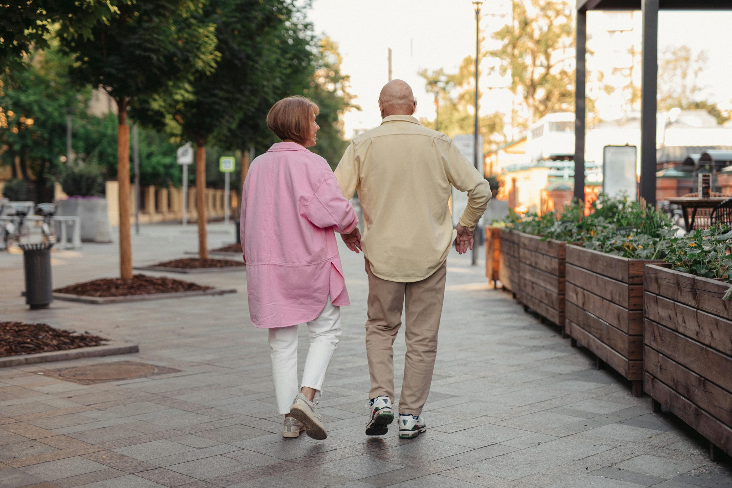Older couple walking together on a landscaped pedestrian path in a quiet neighborhood